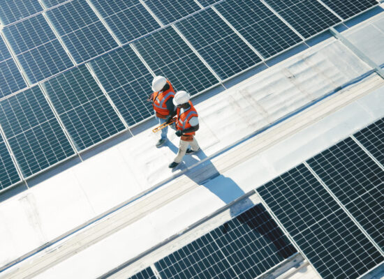 Renewable energy, solar panels and team walking on roof planning for inspection at sustainable business. Engineering, sustainability and photovoltaic power on rooftop, men in electricity maintenance.